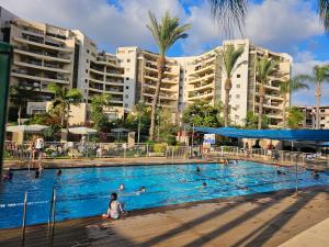 a swimming pool with people in it with buildings at Quiet & Comfortable Room in Raanana with a private bathroom up to 1 guest in Shared Apartment in Ra‘ananna