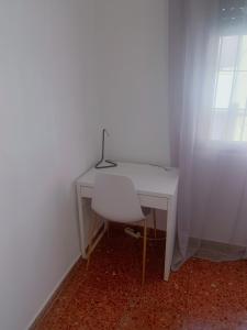 een wit bureau met een stoel en een lamp erop bij Room Valdeolleros in Córdoba