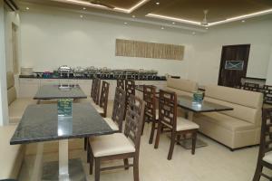 a restaurant with tables and chairs and a kitchen at Avenue 11 Premium Stays Madurai in Madurai