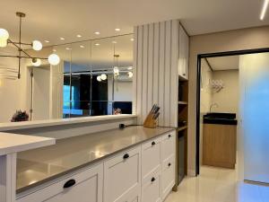 uma cozinha com armários brancos e um espelho grande em Apartamento Beluno 3 dorm Canela by Achei em Canela
