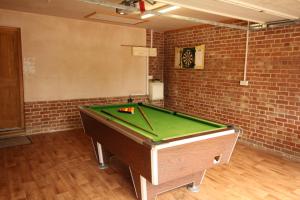 a pool table in a room with a brick wall at Old Oak Barn - Beautiful barn conversion with wonderful Jacuzzi hot tub in Stowmarket