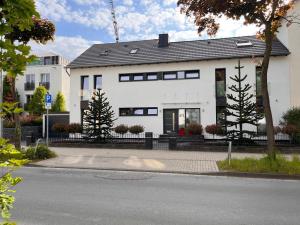 ein weißes Haus mit schwarzen Fenstern auf einer Straße in der Unterkunft Willkommen Zuhause - Traumhafte, zentrale Ferienwohnung in Kurstadt in Bad Oeynhausen