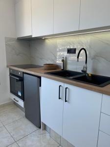 a kitchen with white cabinets and a sink at Elounda Port Apartment in Elounda
