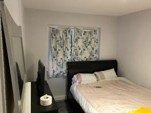 a bedroom with a bed and a window with curtains at Road to home in Abbey Wood