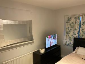 a bedroom with a television on a dresser with a bed at Road to home in Abbey Wood