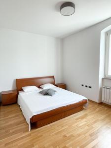 Cette chambre comprend un lit avec des draps blancs et du parquet. dans l'établissement Koper Sea Apartment, à Koper