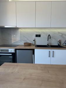 a kitchen with white cabinets and a sink at Elounda Port Apartment in Elounda