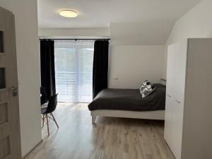 ein Schlafzimmer mit einem Bett, einem Fenster und einem Stuhl in der Unterkunft Roomflacja in Wisła