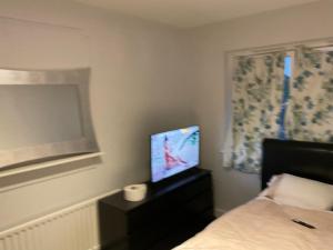 Dormitorio con cama y tocador con TV en Road to home, en Abbey Wood