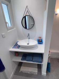 W łazience znajduje się umywalka i lustro. w obiekcie Maison Chez Marinette w mieście Verdun-sur-le-Doubs