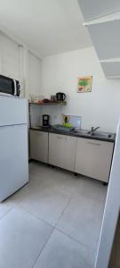 uma cozinha com balcões brancos e um frigorífico branco em Ti-Hibiscus Bungalow T1 Clim-WiFi 30m2 2 pers em Grande Savane