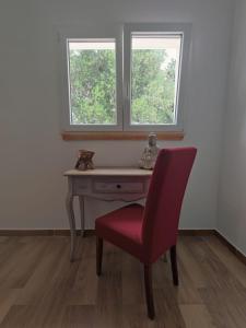 een rode stoel voor een bureau met twee ramen bij Villa Sissy in Ostuni