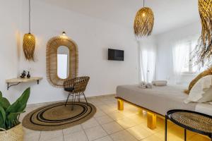 a bedroom with a bed and a mirror and a chair at Ourania Studios & Apartments in Skopelos Town