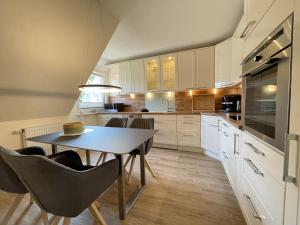 a kitchen with white cabinets and a table and chairs at Ferienwohnung in Wyk-Boldixum auf Foehr in Boldixum
