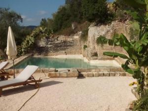 a swimming pool with a chair and an umbrella at Masseria Pelosella B&B in Fasano