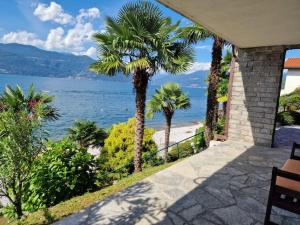 een huis met palmbomen en uitzicht op de oceaan bij Villa La Fenice sulle rive del Lago Maggiore in Porto Valtravaglia