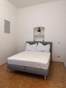 uma cama num quarto com uma parede branca em AlPa 2 Zimmer Wohnung in Wien Rochusmarkt em Viena