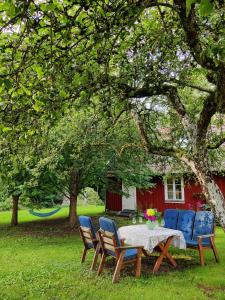 una mesa y sillas bajo un árbol en un patio en Stuga i natursköna mittskåne en Höör