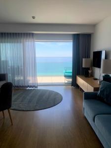 a living room with a couch and a view of the ocean at SESIMBRA SOL in Sesimbra