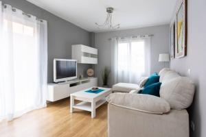 a living room with a white couch and a tv at Cálido apartamento, piscina, Wi-Fi in Candelaria