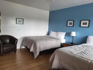 una habitación de hotel con 2 camas y una silla en Sherbrooke Village Inn, en Sherbrooke