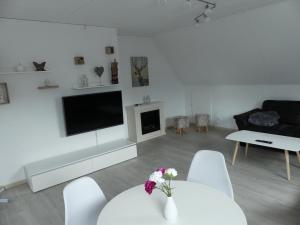 a white living room with a table and a tv at FeWo Maschblick in Schwarmstedt