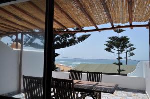 een tafel en stoelen op een balkon met uitzicht op het strand bij KABANO BEACH AUBERGE CAFE RESTAURANT in Moulay Bousselham