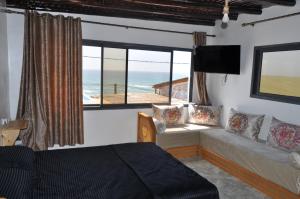 een slaapkamer met een bed en uitzicht op de oceaan bij KABANO BEACH AUBERGE CAFE RESTAURANT in Moulay Bousselham