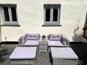 three wicker chairs and tables in front of a building at Stunning Cottage Close to Amazing Beaches in Braunton