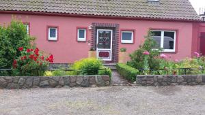 ein rosa Haus mit Blumen davor in der Unterkunft Haus am Teich - Teichblick in Fehmarn
