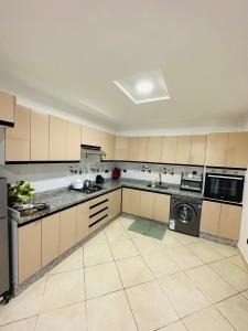 a large kitchen with tan cabinets and a dishwasher at Petite villa a hay dakhla in Agadir
