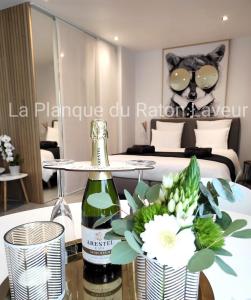 Zimmer mit einer Flasche Wein und Blumen auf dem Tisch in der Unterkunft La planque du raton laveur in Lierneux