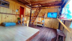 ein Wohnzimmer mit einem TV und einer Holzwand in der Unterkunft Tổ Chim Ri Homestay Măng Đen in Kon Von Kla