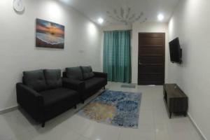sala de estar con sofá negro y TV en KITAKAYA Homestay Kota Bharu - 8 Pax, en Kota Bharu