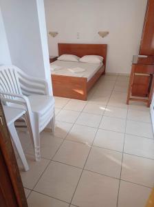 una camera con letto, sedia e pavimento piastrellato di Georgina ad Agia Marina Nea Kydonias