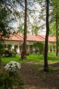 uma casa com árvores e flores no quintal em Noclegi Pod Dębem u Jakuba em Niepołomice