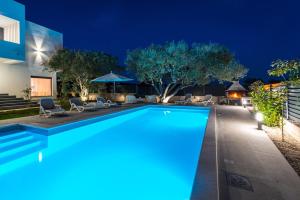 a swimming pool in the middle of a house at night at CROWONDER Sun Dance Apartments with Heated Swimming Pool Seaview and Garden in Sveti Filip i Jakov