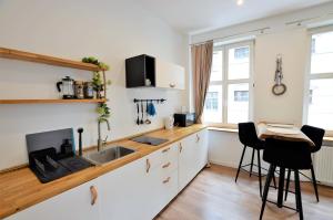 a kitchen with white cabinets and a sink and a table at Apartament Szeroka Old Town in Gdańsk