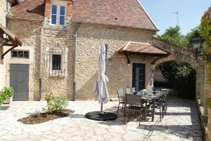 eine Terrasse mit einem Tisch und einem Sonnenschirm in der Unterkunft Le Prieuré: maison de charme proche de Vézelay**** 
