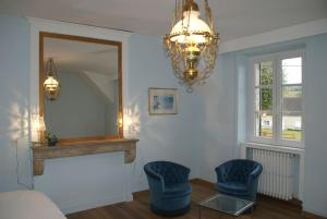 ein Wohnzimmer mit 2 blauen Stühlen und einem Spiegel in der Unterkunft Le Prieuré: maison de charme proche de Vézelay**** 