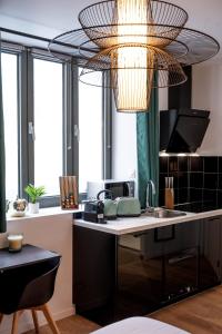 een keuken met een wastafel en een kroonluchter bij Appart-hôtel de standing avec jacuzzi privatisable en option in Périgueux