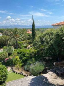 een tuin met bomen en struiken en een bank bij Nouveau Villa vue mer, proche centre et plage in Fréjus