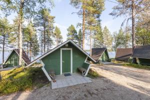 a green house with a porch and a bench at Ranua Resort Camping Ranuanjärvi in Ranua