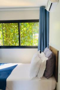 a bedroom with a window and a bed with pillows at Maritimus Suites Apartamento 07 in Barretos