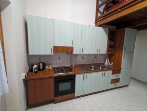 una cucina con armadi bianchi, piano cottura e lavandino di Sciacca Holiday Home a Sciacca