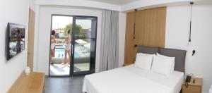 a bedroom with a white bed and a balcony at The Oak Hotel in Keramotí