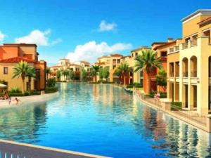 a canal in a city with buildings and palm trees at Home in Marassi in El Alamein