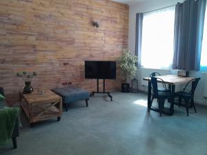 a living room with a wooden wall with a table and a television at Apartmán Maya in Pardubice