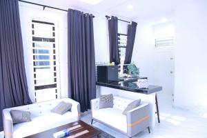 ein Wohnzimmer mit 2 weißen Stühlen und einem Tisch in der Unterkunft Green Dream Homestay 2 Kota Bharu Town 3 Aircond Room With Wifi & Netflix in Kota Bharu