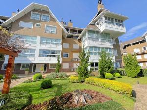ein großes Apartmenthaus mit einem Garten davor in der Unterkunft Espaçoso apto no Centro de Gramado in Gramado